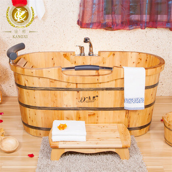 Runde Holzbadewanne im Badezimmer mit Wasserhahn, Handtuch und kleinem Holzpodest