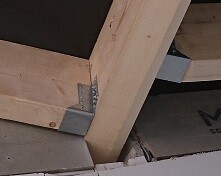 Nahaufnahme einer Holzrahmenkonstruktion im Rohbau mit Metallwinkelverbindungen.