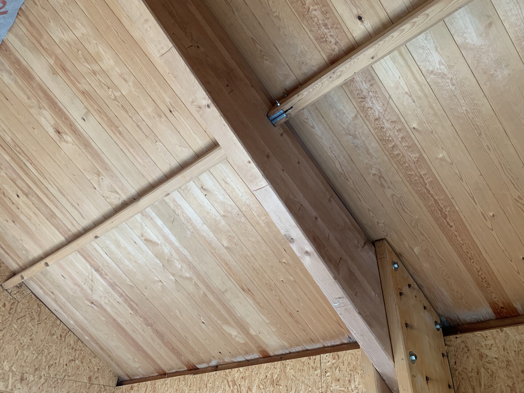 Dachstuhl aus Holz mit Balken, Brettern und sichtbaren Bolzen