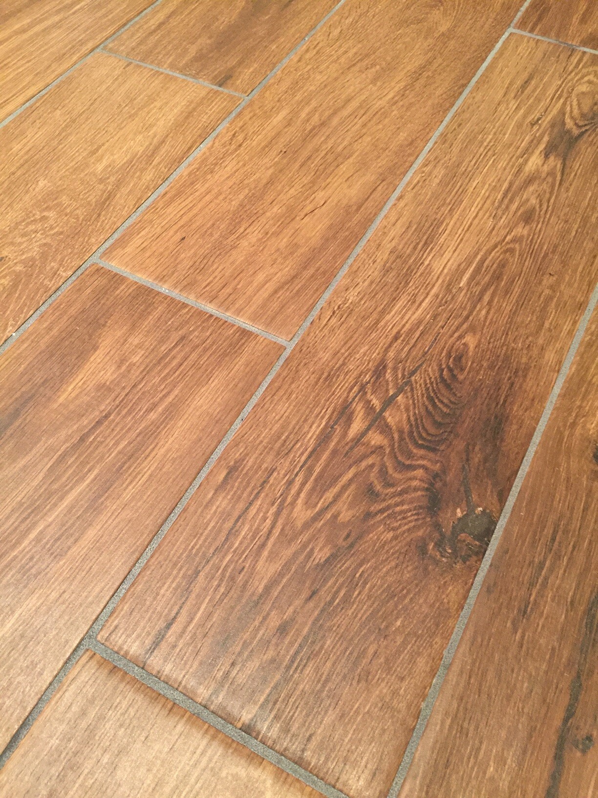 Holzfußboden aus braunen Planken mit Maserung und grauen Fugen.