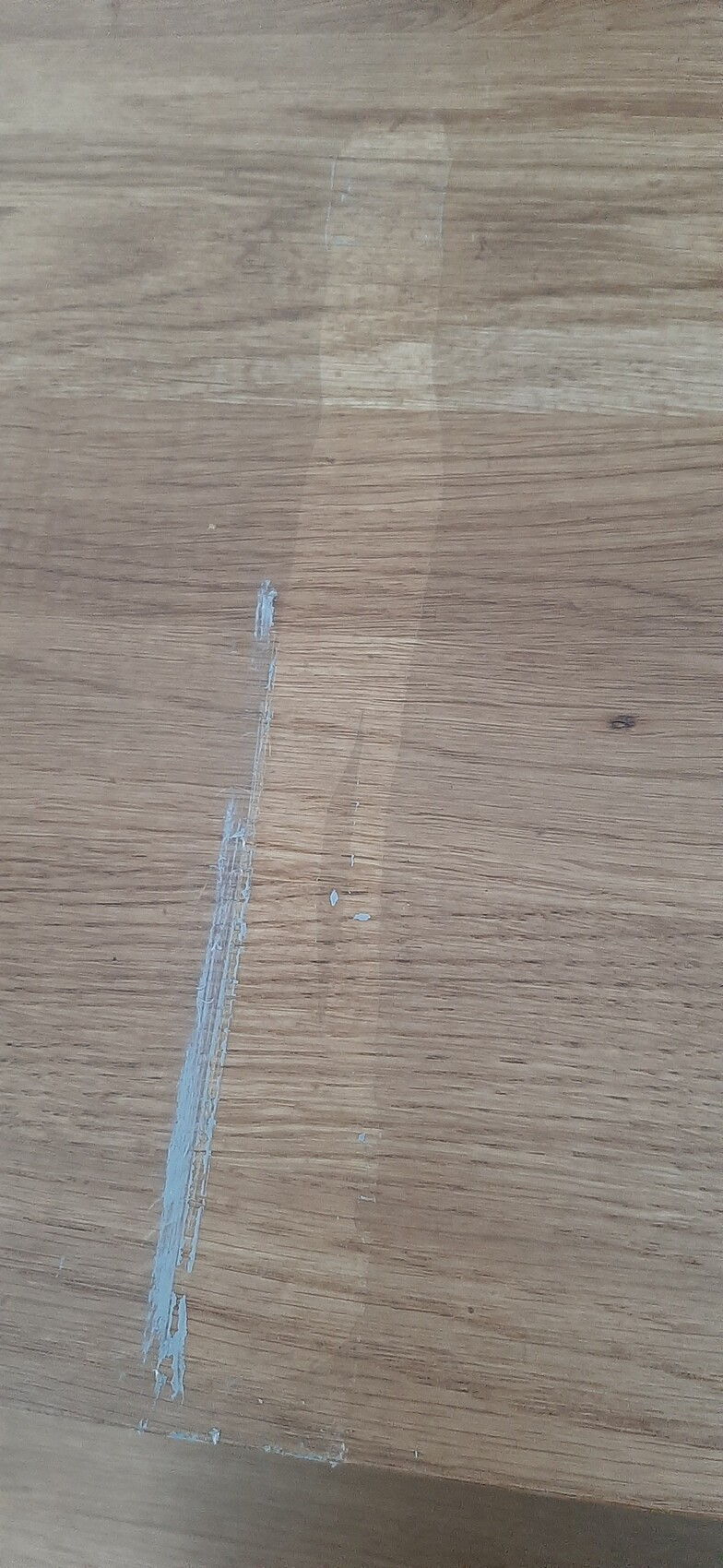 Holztischplatte mit langem, transparentem Klebebandstreifen von oben nach unten.