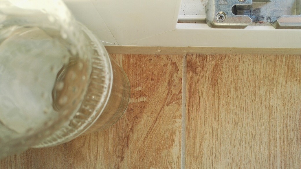 Nahaufnahme eines Holz- bzw. Laminatbodens mit Fugen neben Türrahmen