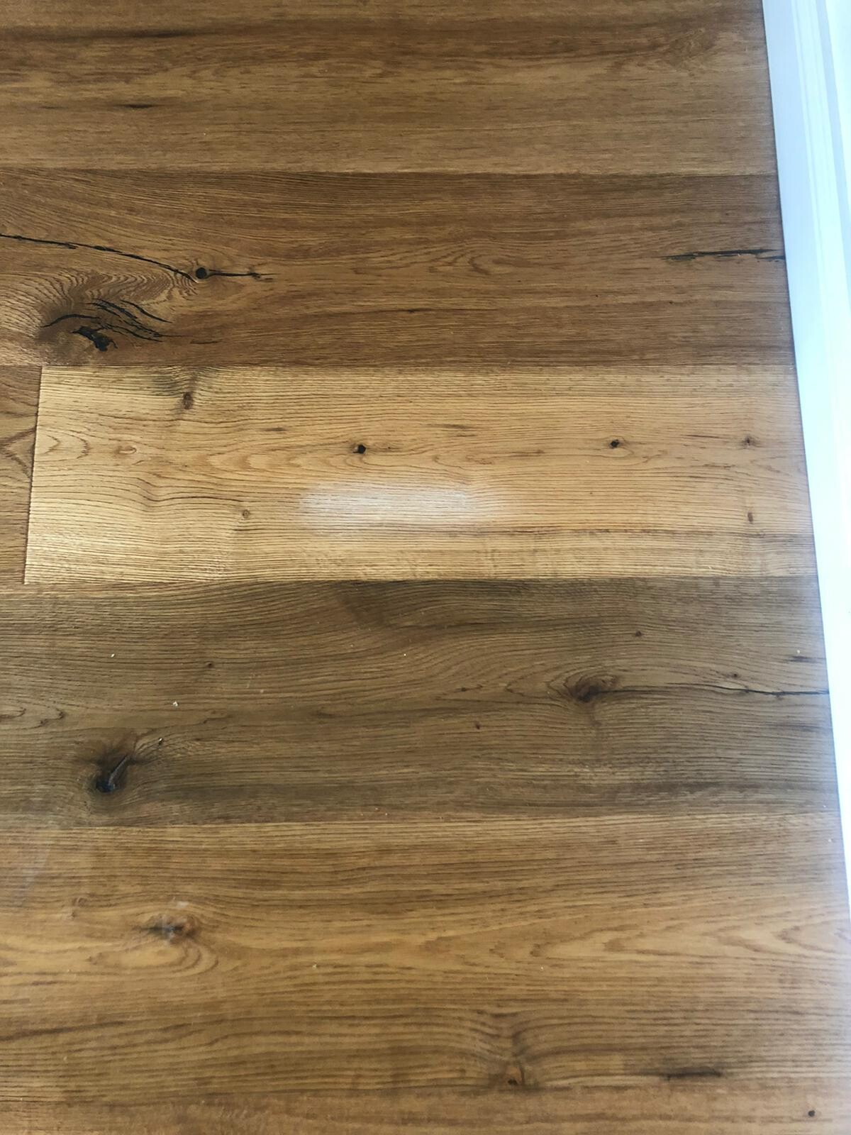 Holzfußboden mit sichtbarer Maserung, Knoten und Farbwechsel; rechter Bildrand Türrahmen.