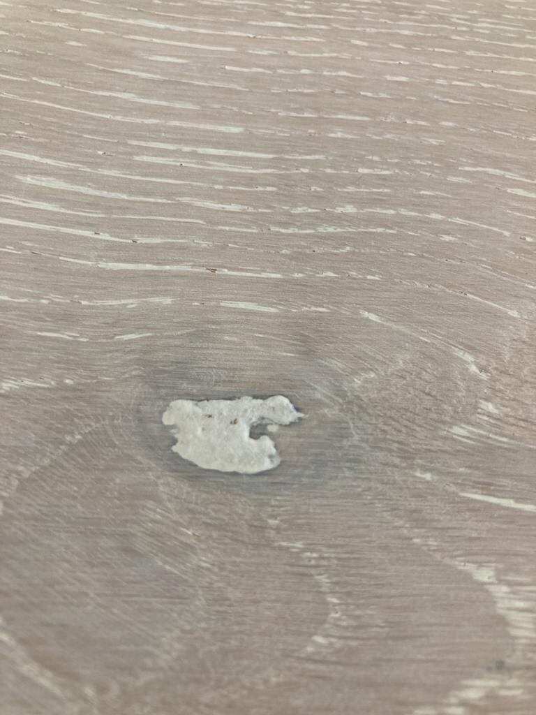 Nahaufnahme eines hellen Holzbodens mit kleinem unregelmäßig geformtem weißen Fleck