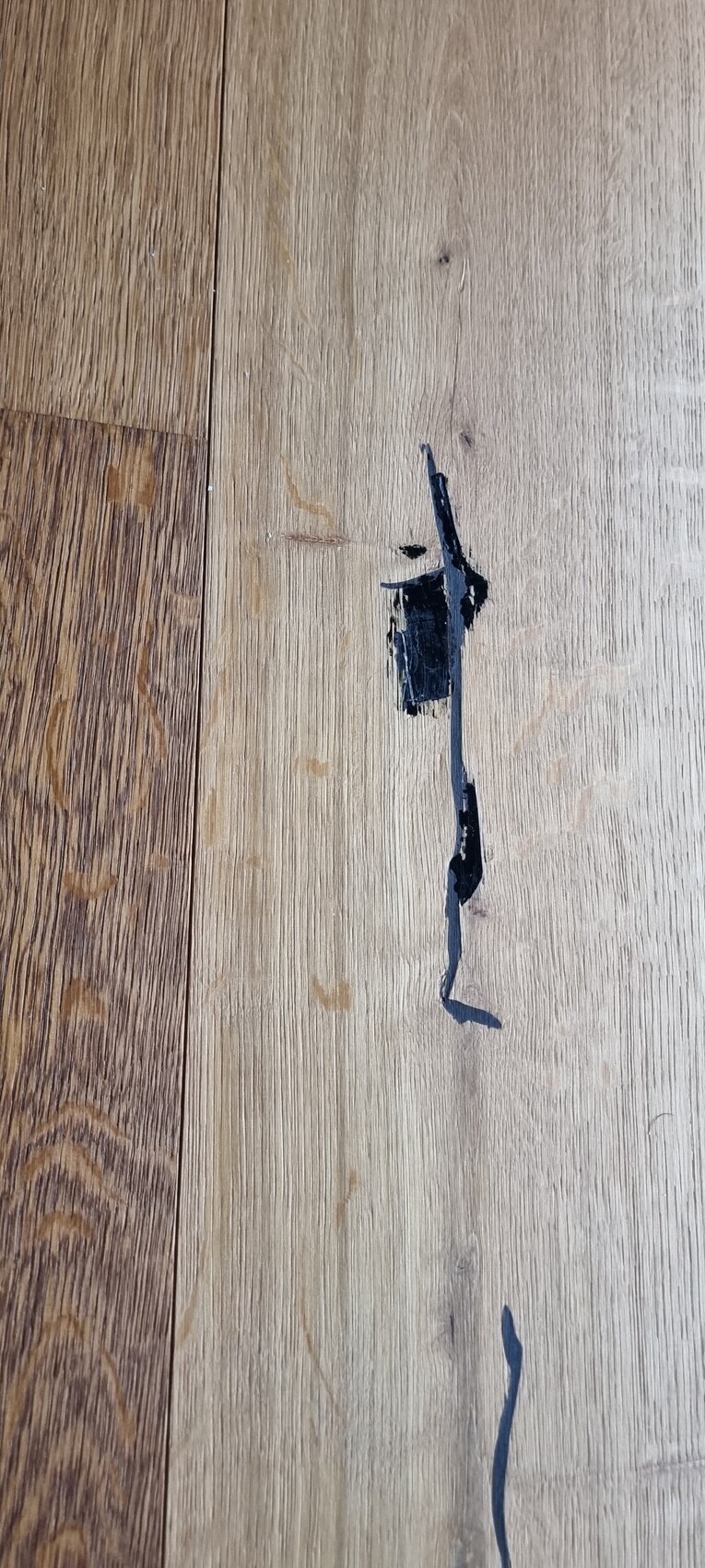 Holzboden mit dunkler Linie in der Fuge zwischen Holzbrettern und schwarzem Patch.