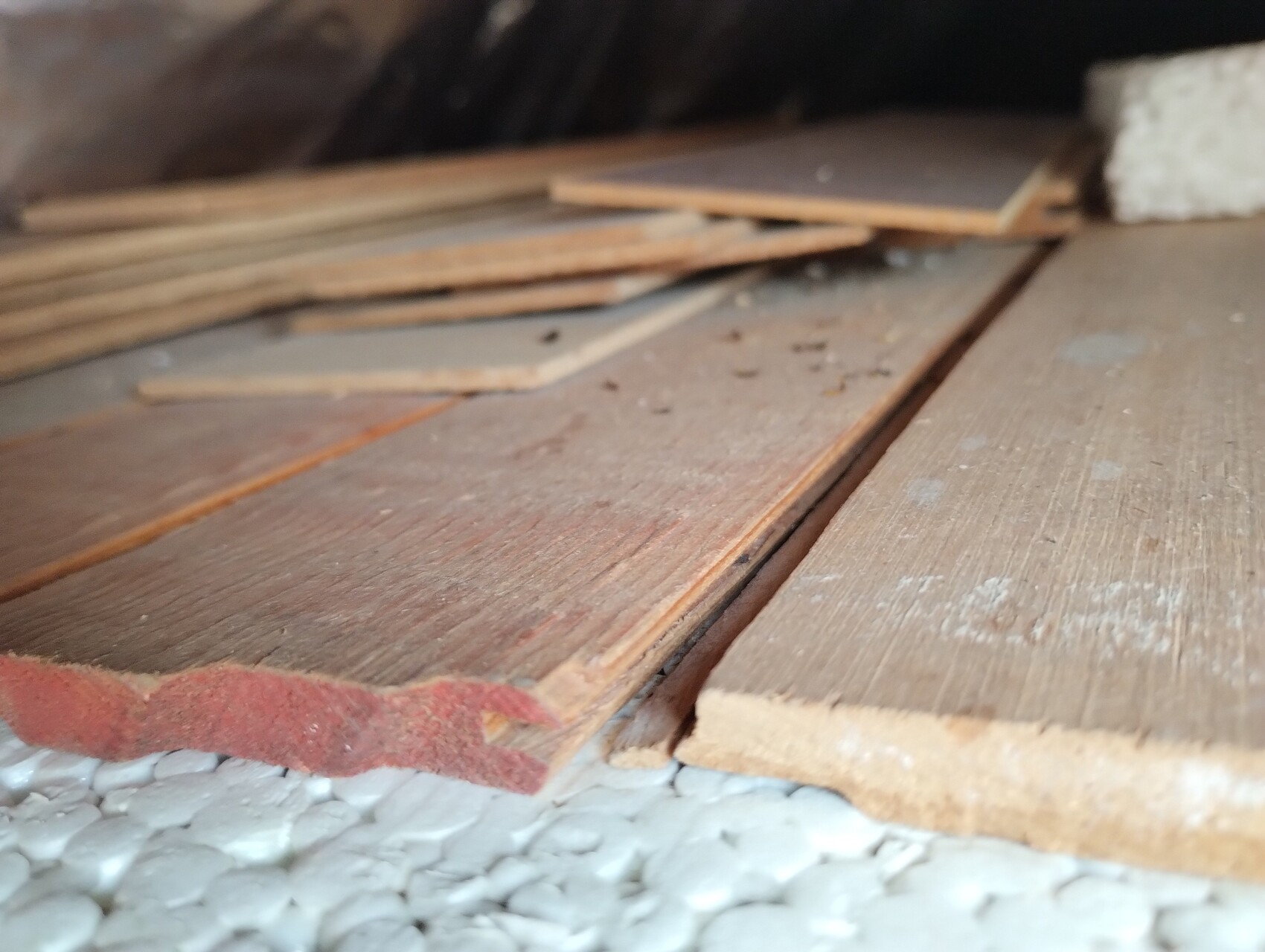 Auf dem Boden liegen mehrere Holzbretter mit Staub und Bauabfällen verstreut.