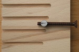 Nahaufnahme eines Holzbretts mit einer großen Schraube durch eine Nut