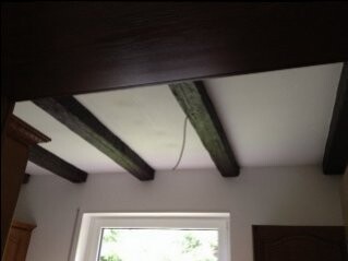 Zimmer mit freiliegenden Holzbalken an Decke und Fenster im Hintergrund