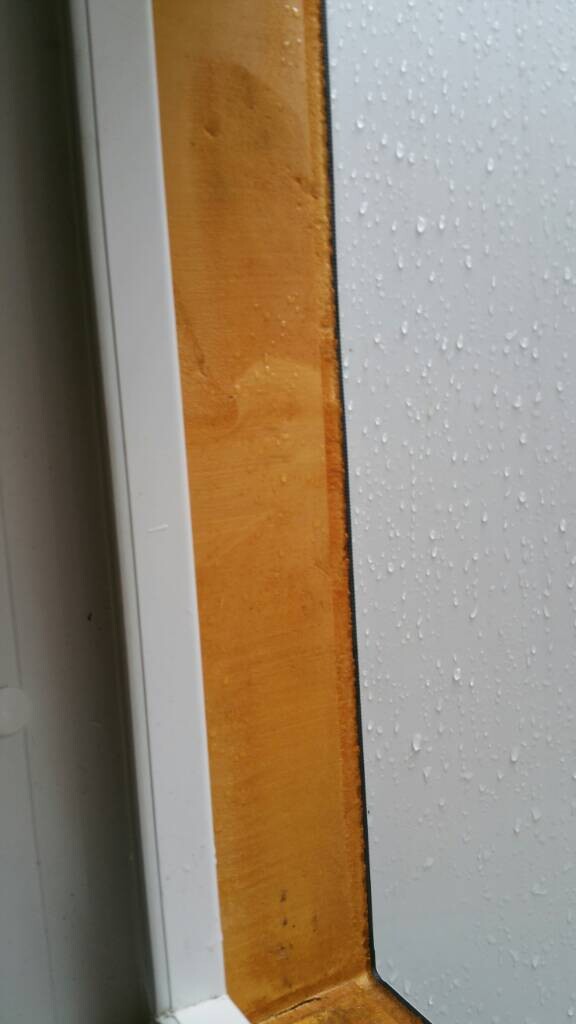 Nahaufnahme eines Holzfensterrahmens mit regennasser Glasoberfläche