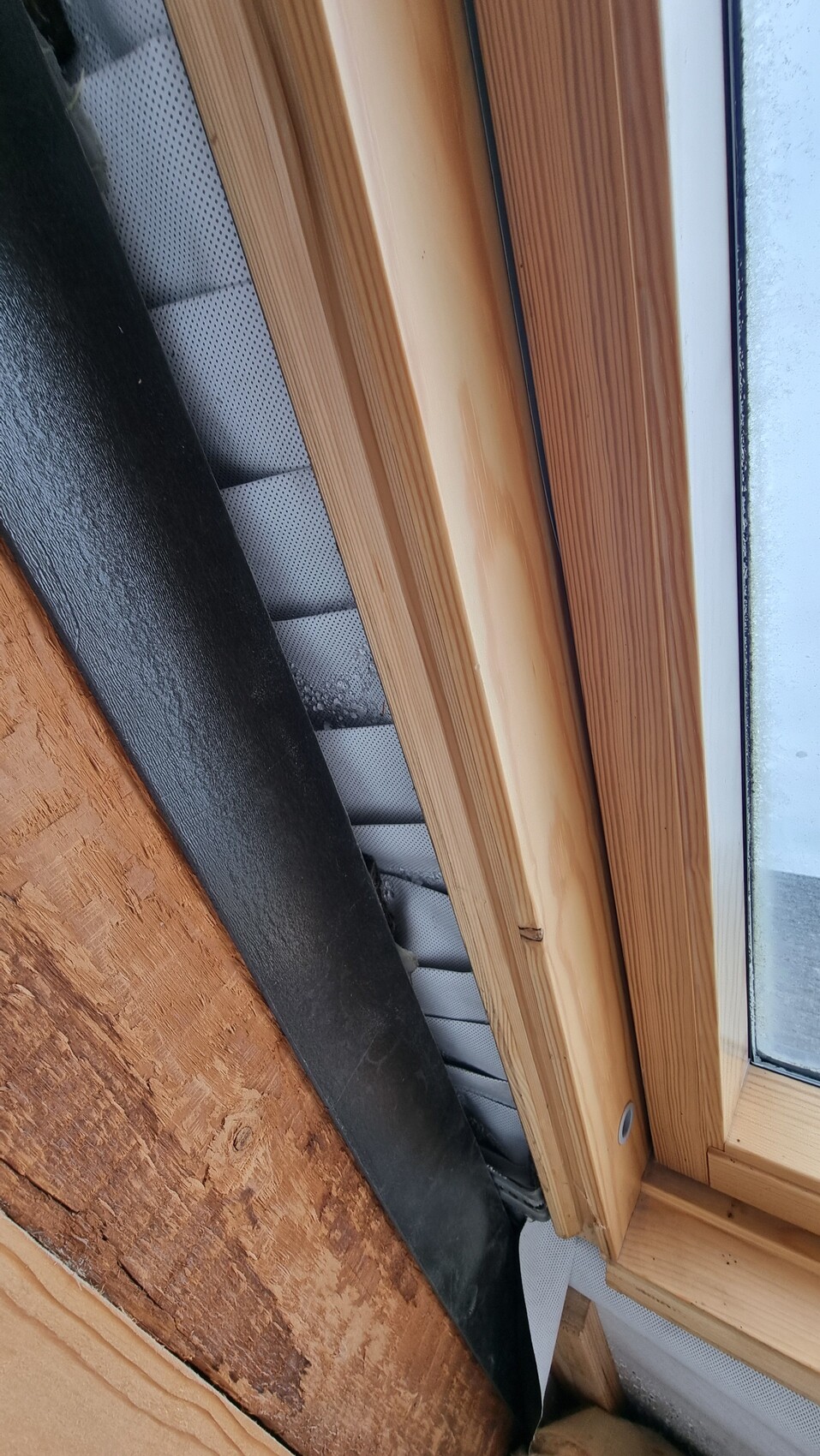 Nahaufnahme eines Holzfensterrahmens mit Glas, Dichtung und Dämmmaterial am Rand