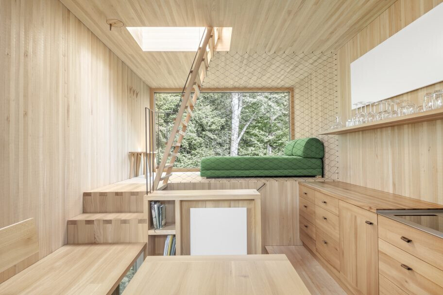 Helles-Holzhaus-Innenraum-Loft-Wohnzimmer-mit-gruenem-Sofa-und-Kueche