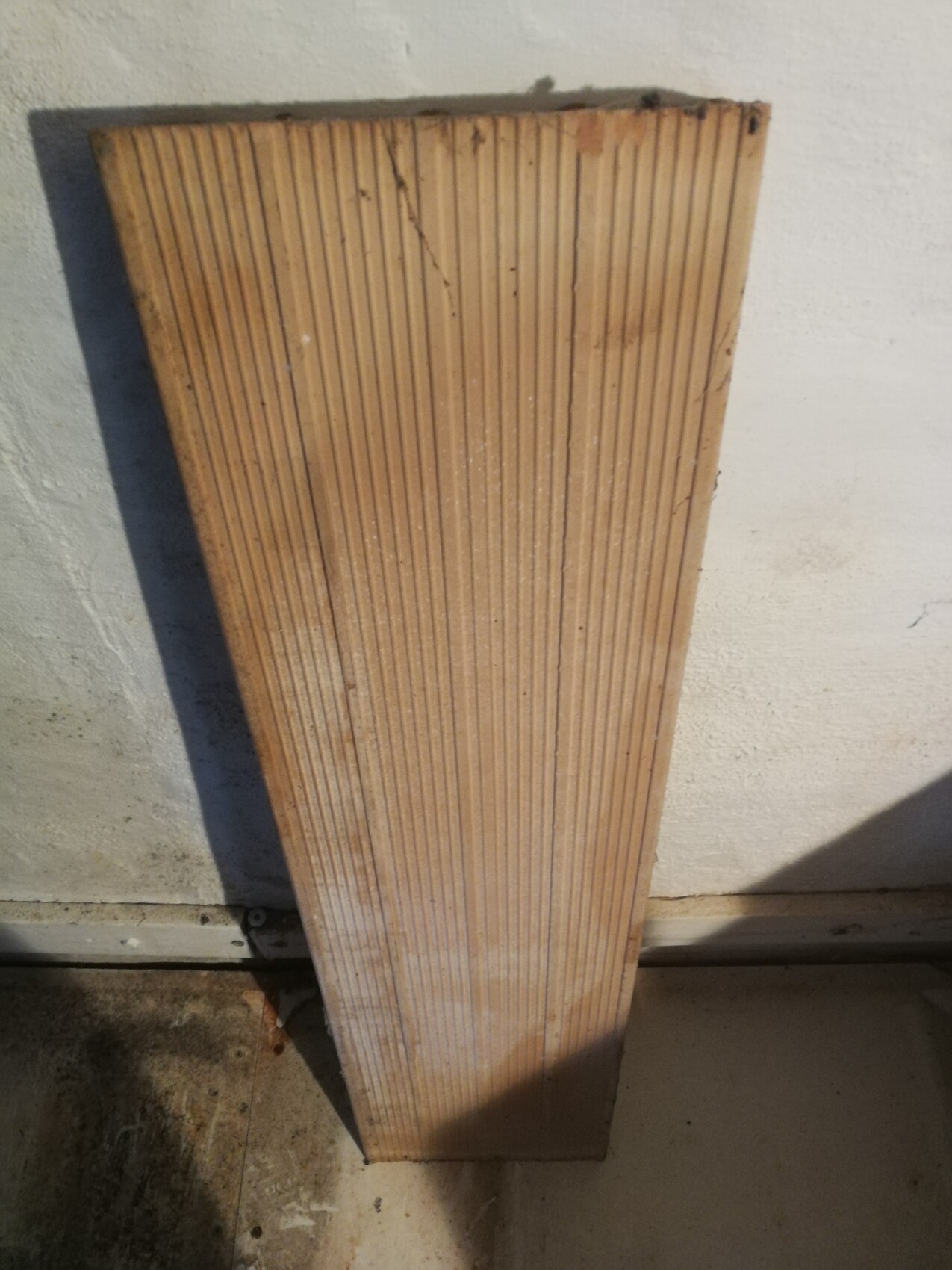 Vertikale geriffelte Holzwandplatte lehnt an einer weißen Wand in einem Baubereich