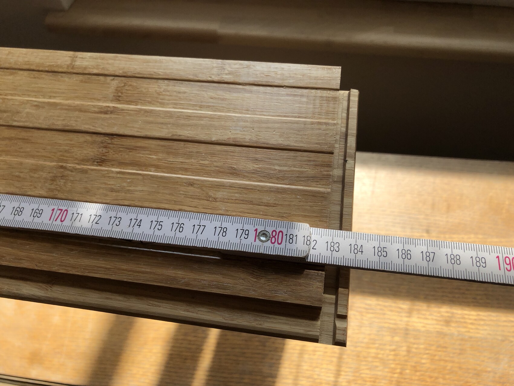 Holzleisten mit Maßband auf Holzuntergrund, Baumaterialien