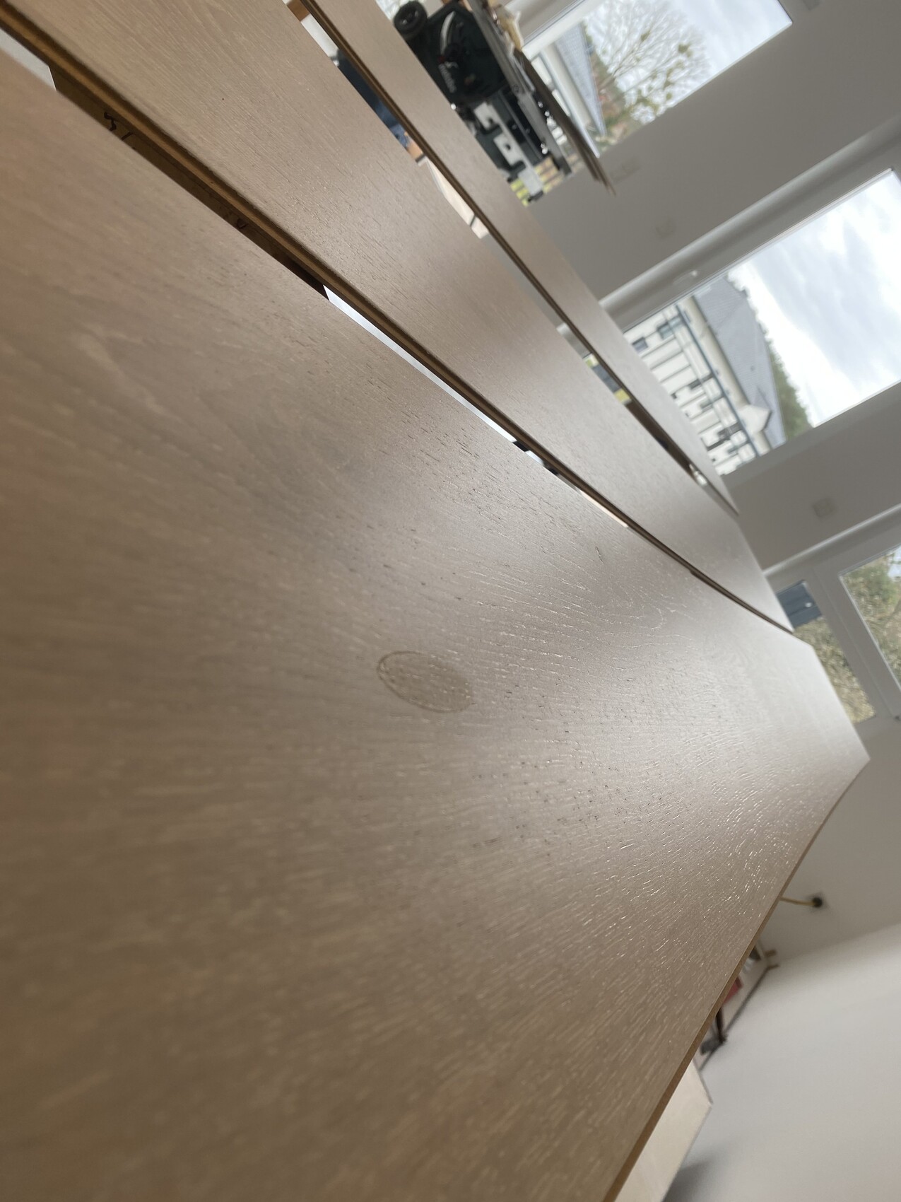 Nahaufnahme eines langen Holztisches mit Maserung und Fenster im Hintergrund