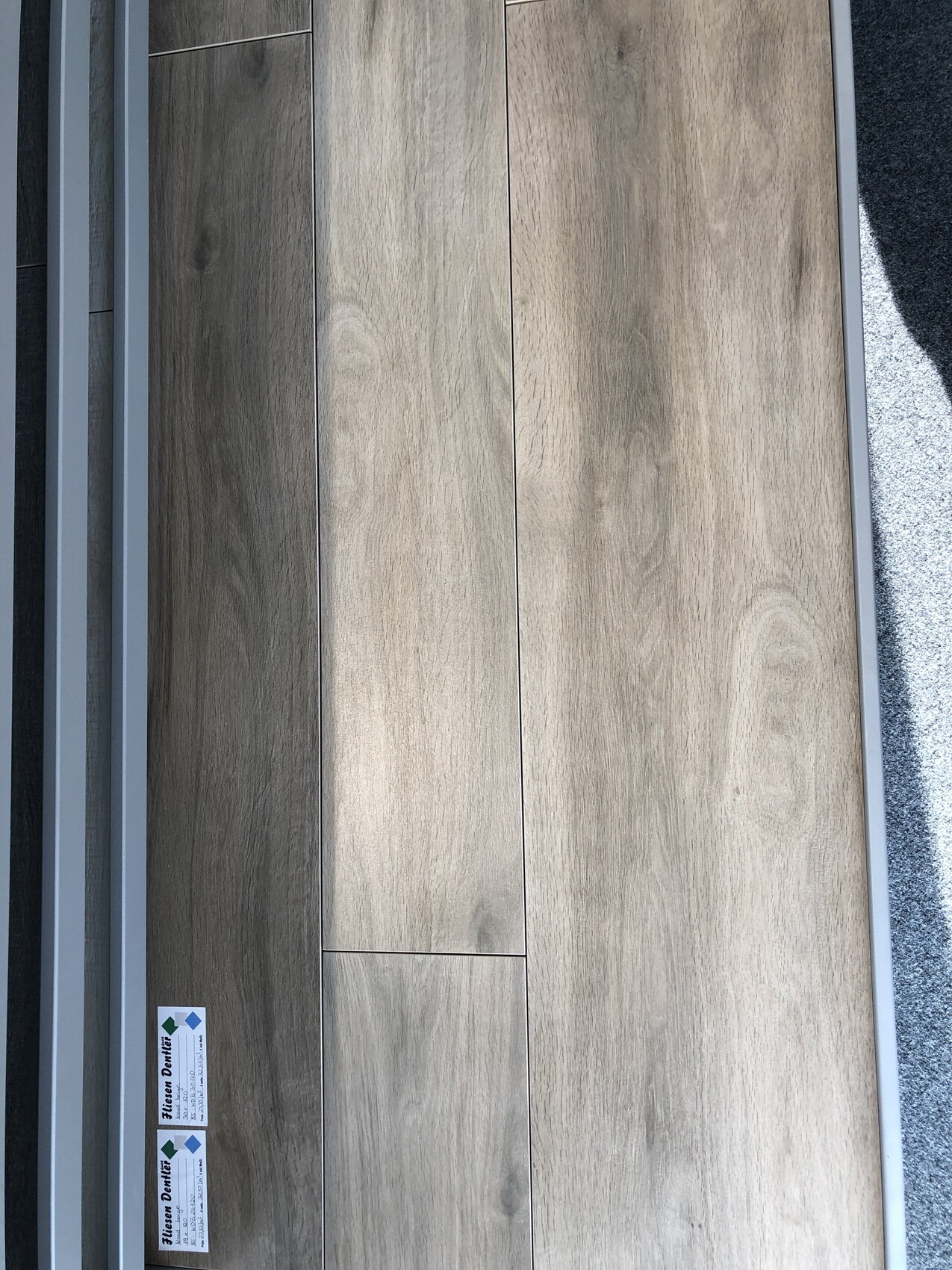Boden aus grauen Holzplanken mit Metallrahmen, Nahaufnahme.