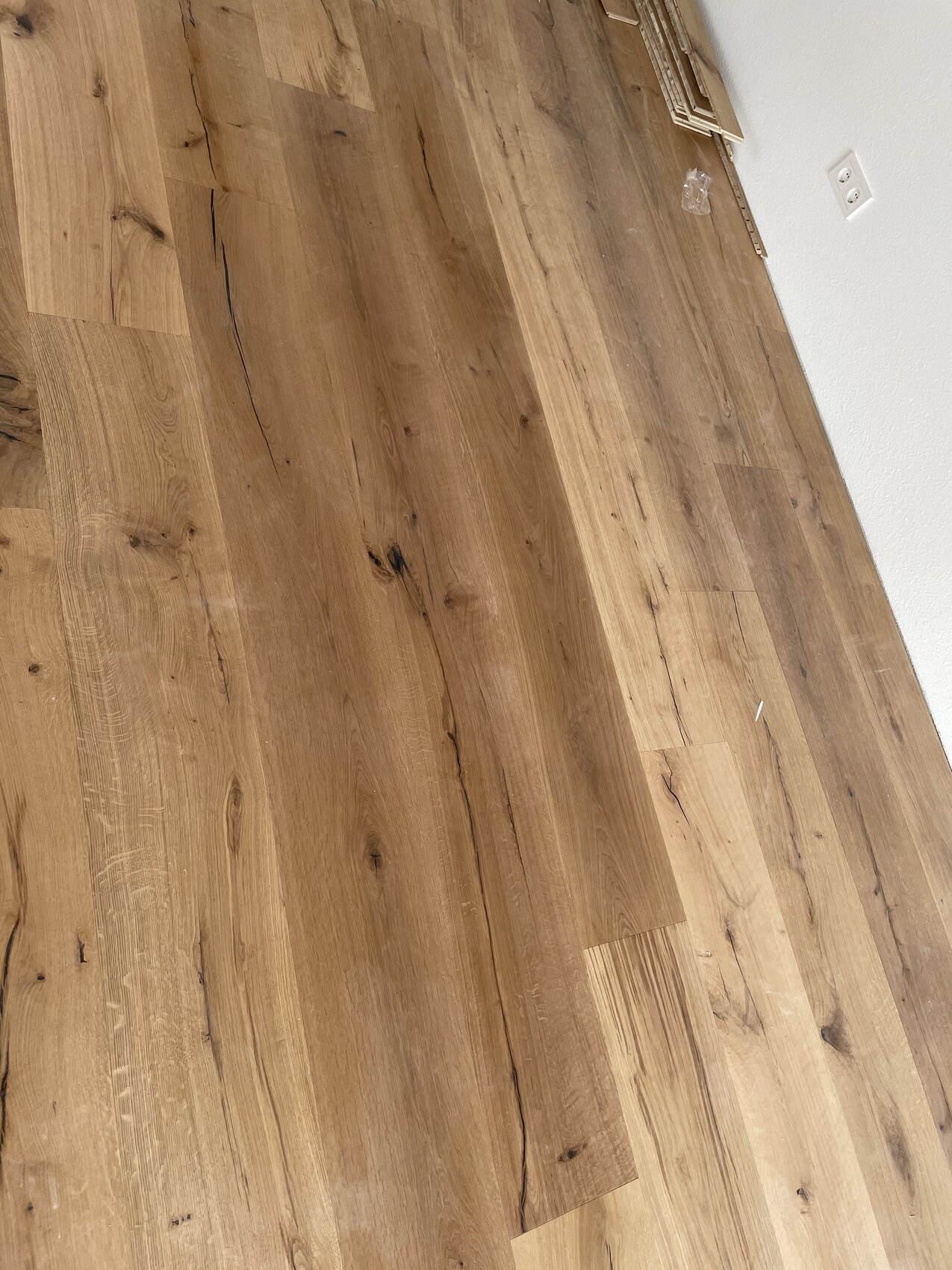 Holzoptik-Bodenbelag aus Laminat, teilweise verlegt, Wandsteckdose sichtbar
