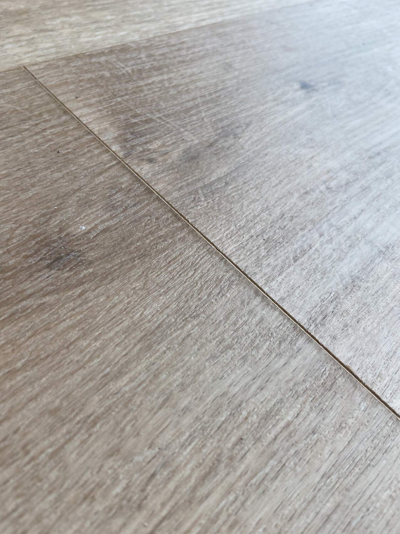 Nahaufnahme eines Holzbodens mit sichtbarer Fuge zwischen zwei Dielen.