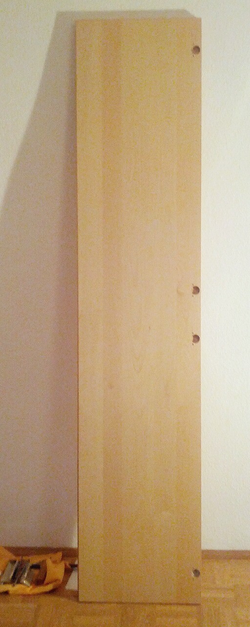 Hochkant stehendes Holzpaneel mit Bohrlöchern an der Kante im Innenraum.