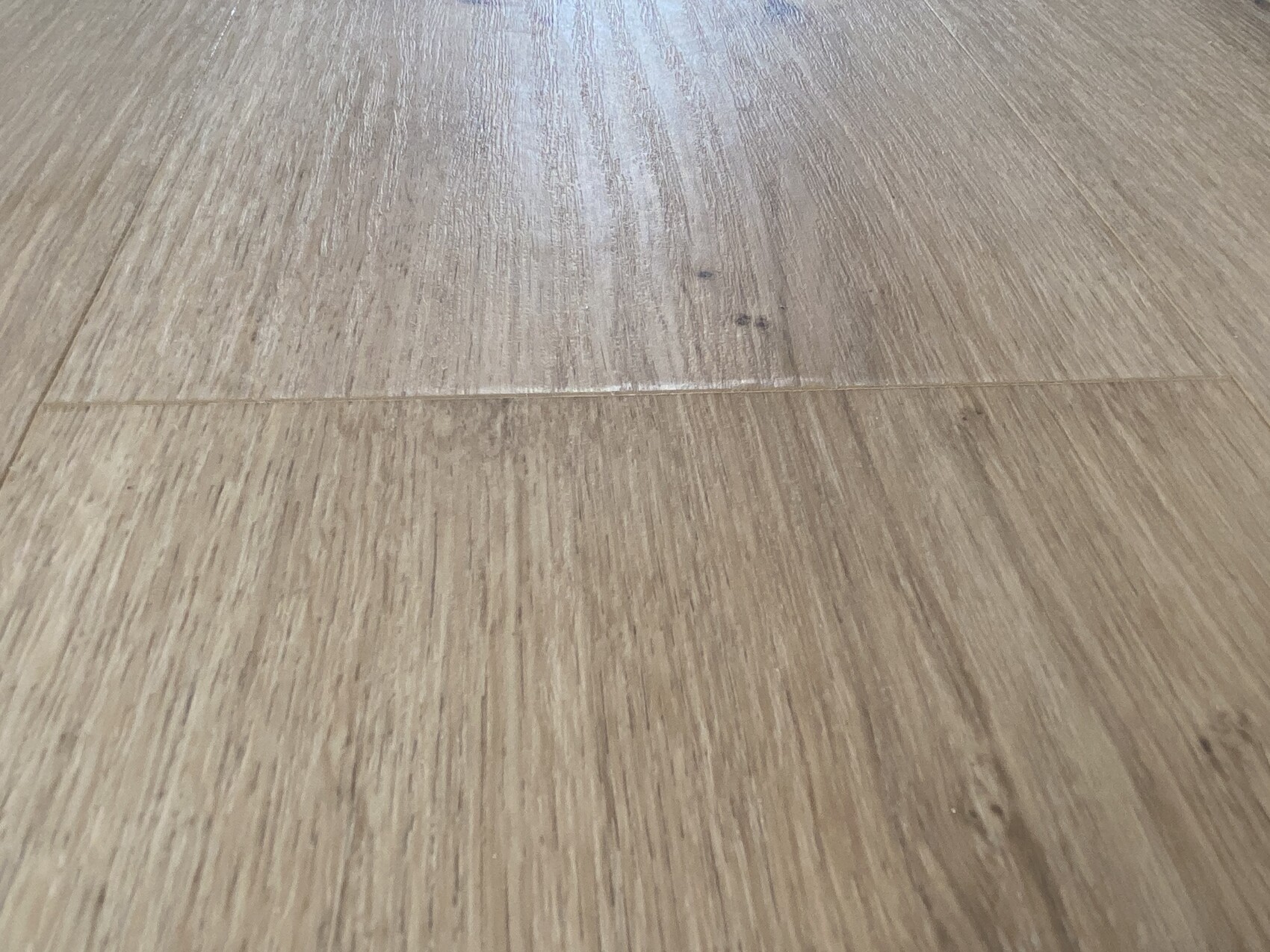 Nahaufnahme eines Holzbodens mit sichtbarer Fuge zwischen Dielen und Maserung.