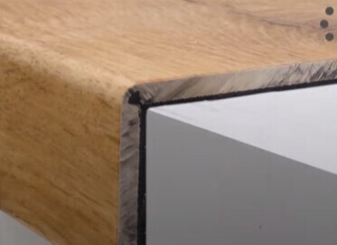 Nahaufnahme einer Holzplatte mit metallischer Kantenverkleidung