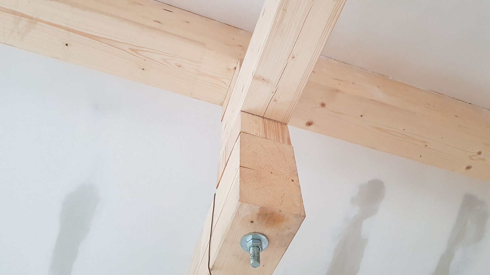 Holzrahmenkonstruktion mit Bolzenverbindung im Rohbau-Deckenbereich.