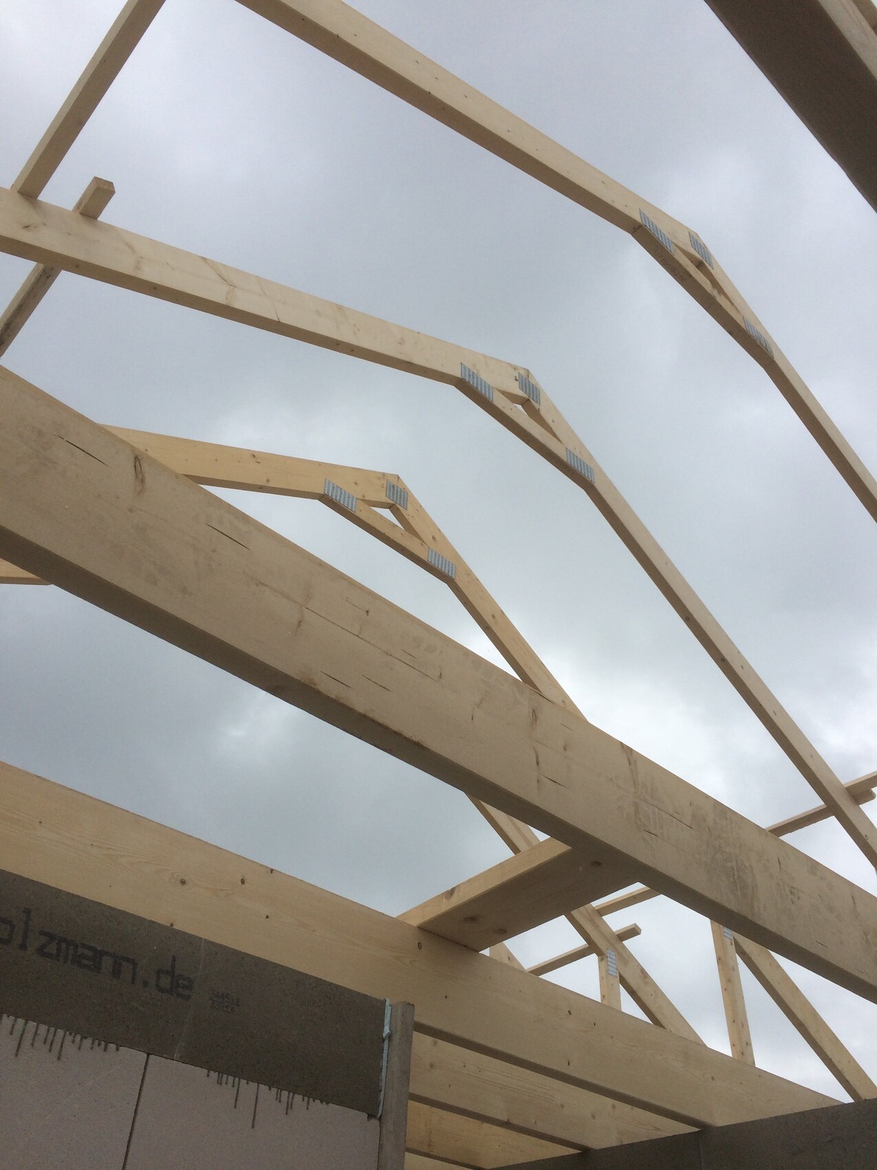 Holz-Dachstuhlrahmen eines Neubauhauses aus Balken vor wolkigem Himmel