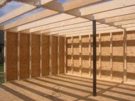 Holzständerwerk im Rohbau Innenraum mit freigelegten Holzwänden und Sonneneinstrahlung