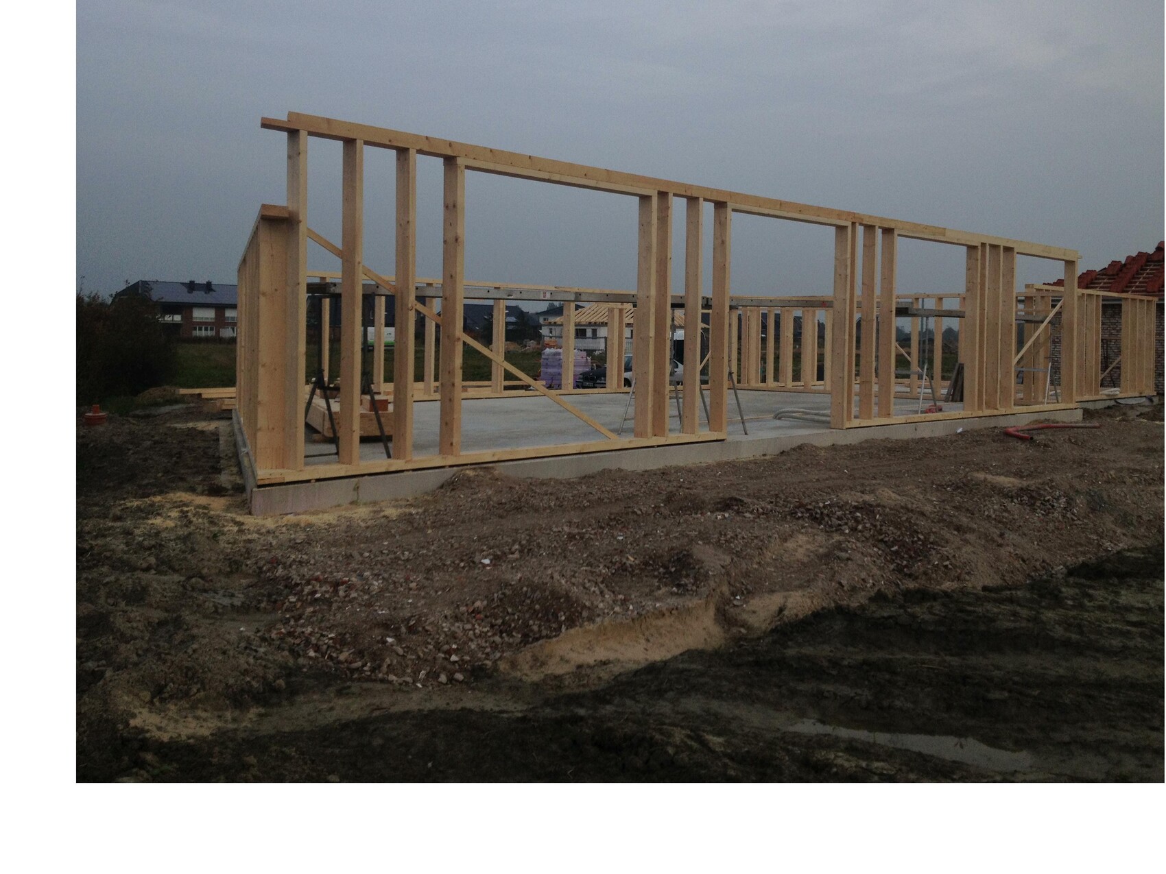 Holzständerkonstruktion eines Neubaus auf Betonfundament, Baustelle mit freiliegenden Ständern.