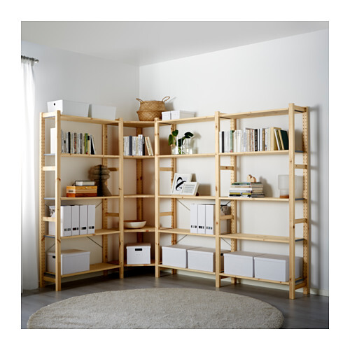 Hölzernes Eckregal im Wohnzimmer mit Büchern, Ordnern und Aufbewahrungsboxen, runder Teppich.