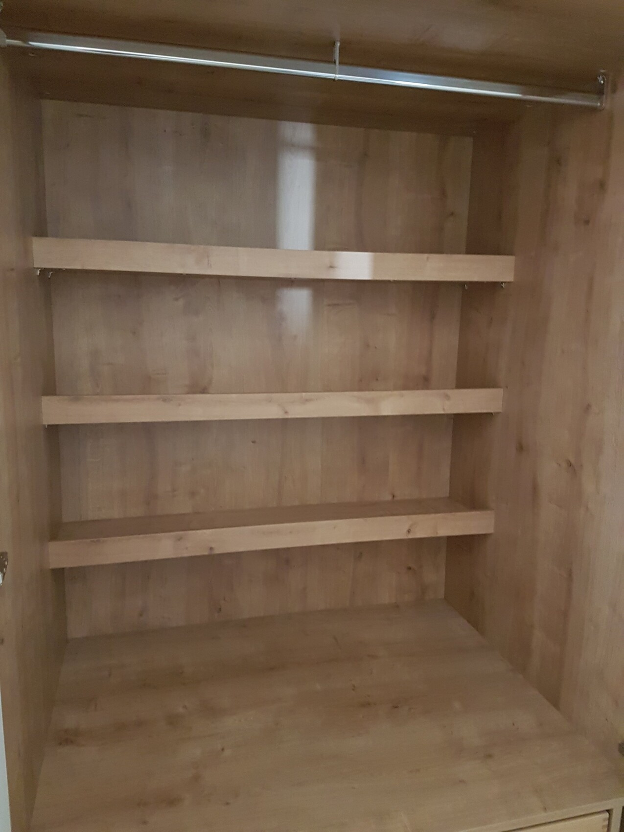 Offener Kleiderschrank mit Holzregalen und Garderobenstange