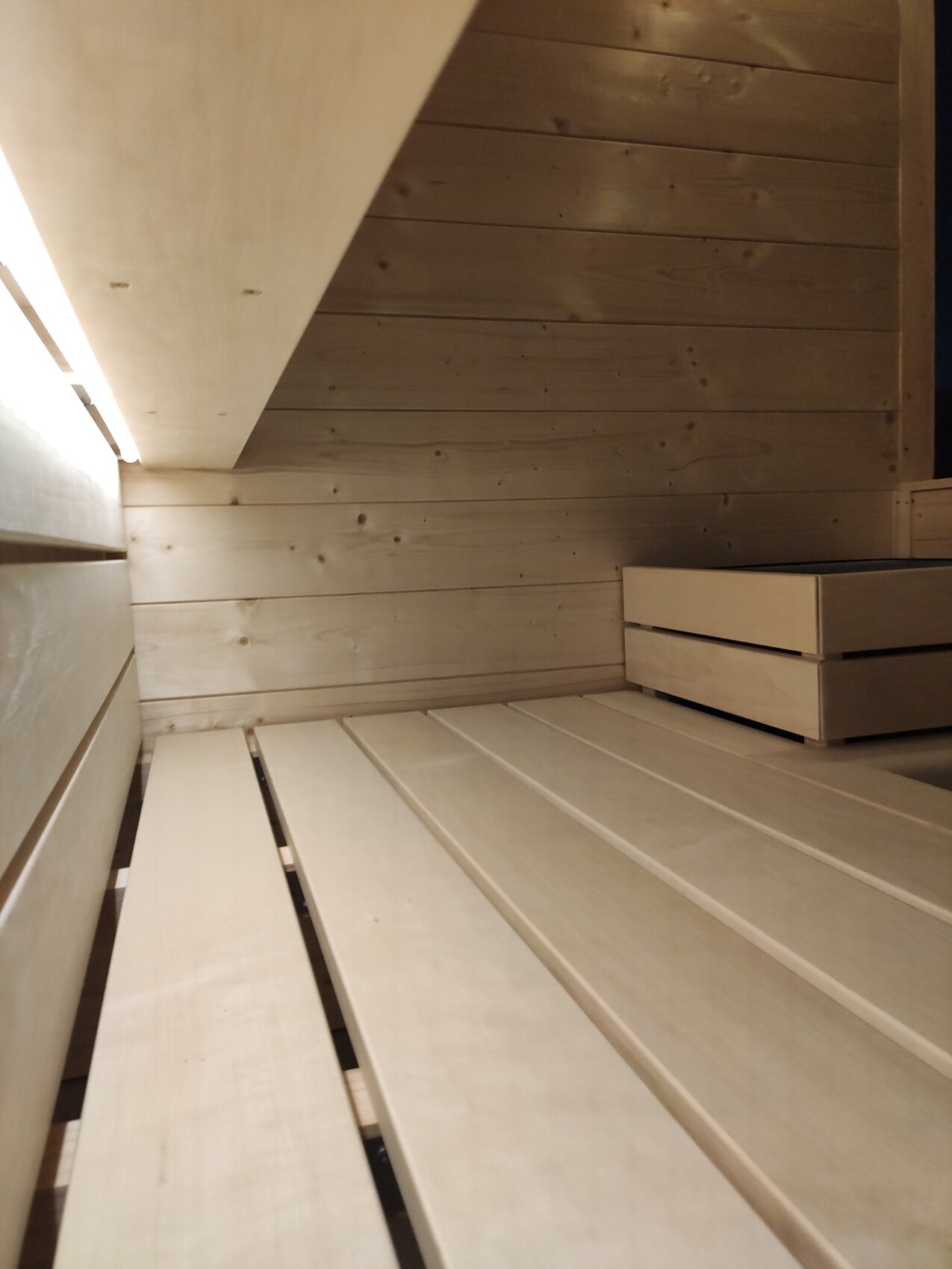 Holzsauna-Innenraum mit mehreren Bankreihen, Holzwänden und warmer Beleuchtung.