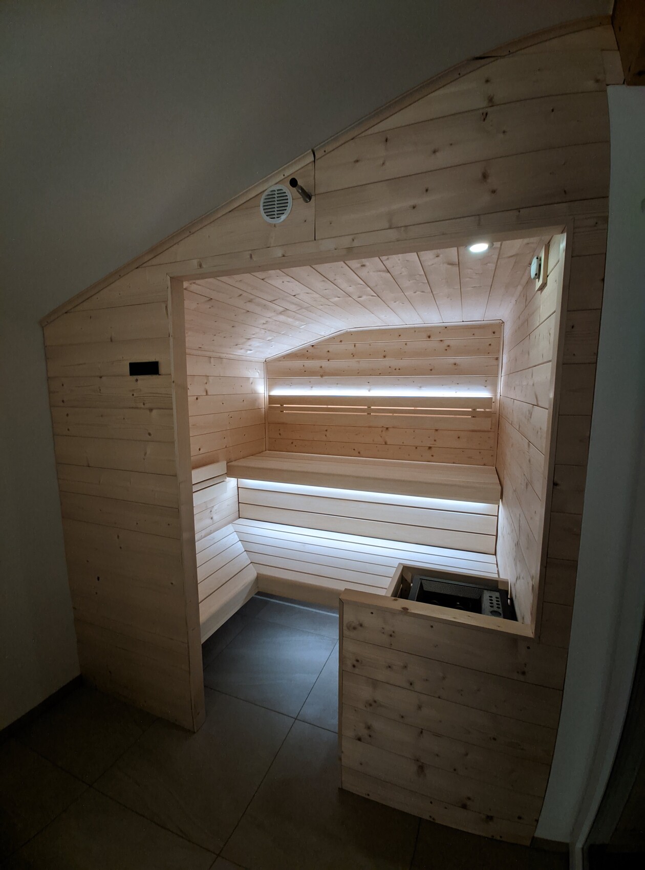 Innenansicht einer Holzsauna mit Sitzbänken und Heizofen