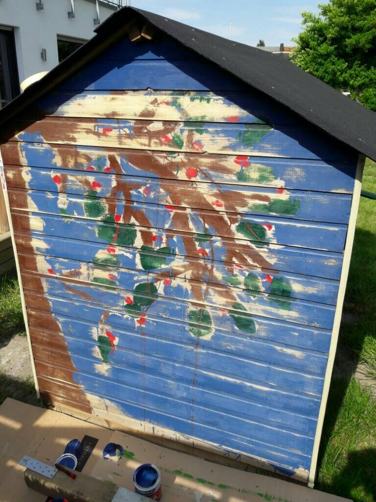 Holzschuppen im Garten mit bunten Farbflecken bemalt