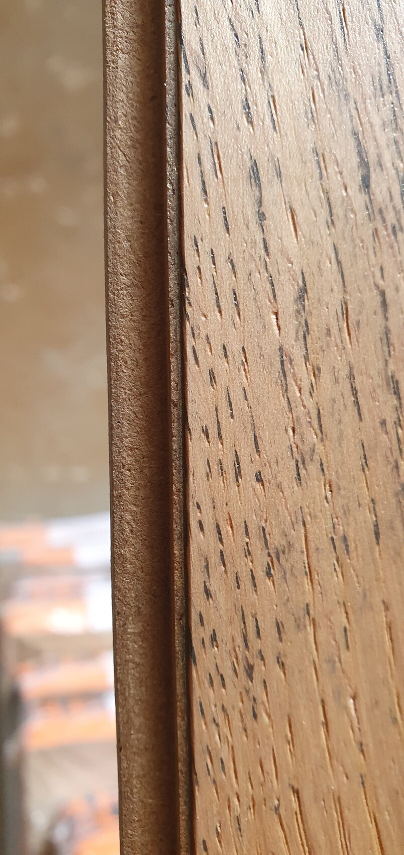 Nahaufnahme von zwei Holzleisten: links dunkler Rand, rechts heller Holzmaserung.