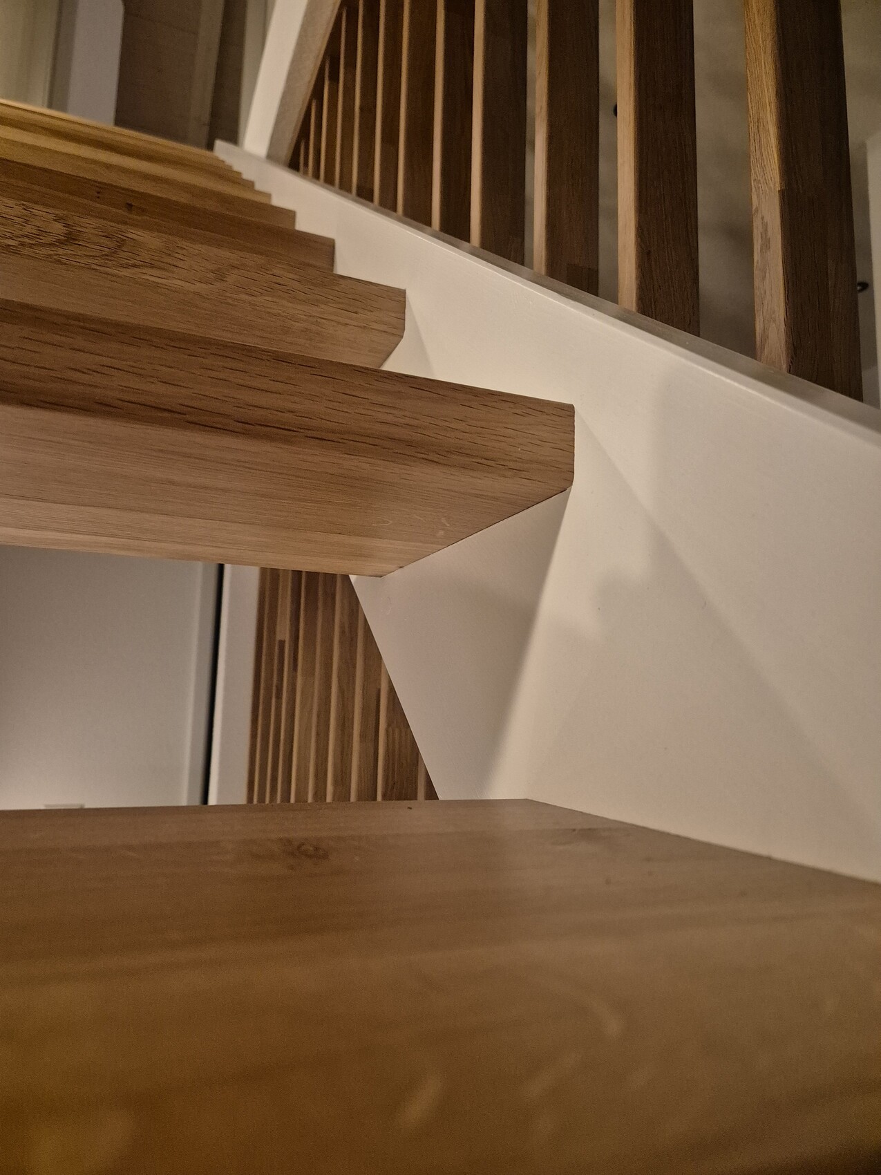 Holztreppe im Innenbereich mit hellbraunen Stufen und weißer Seitenverkleidung