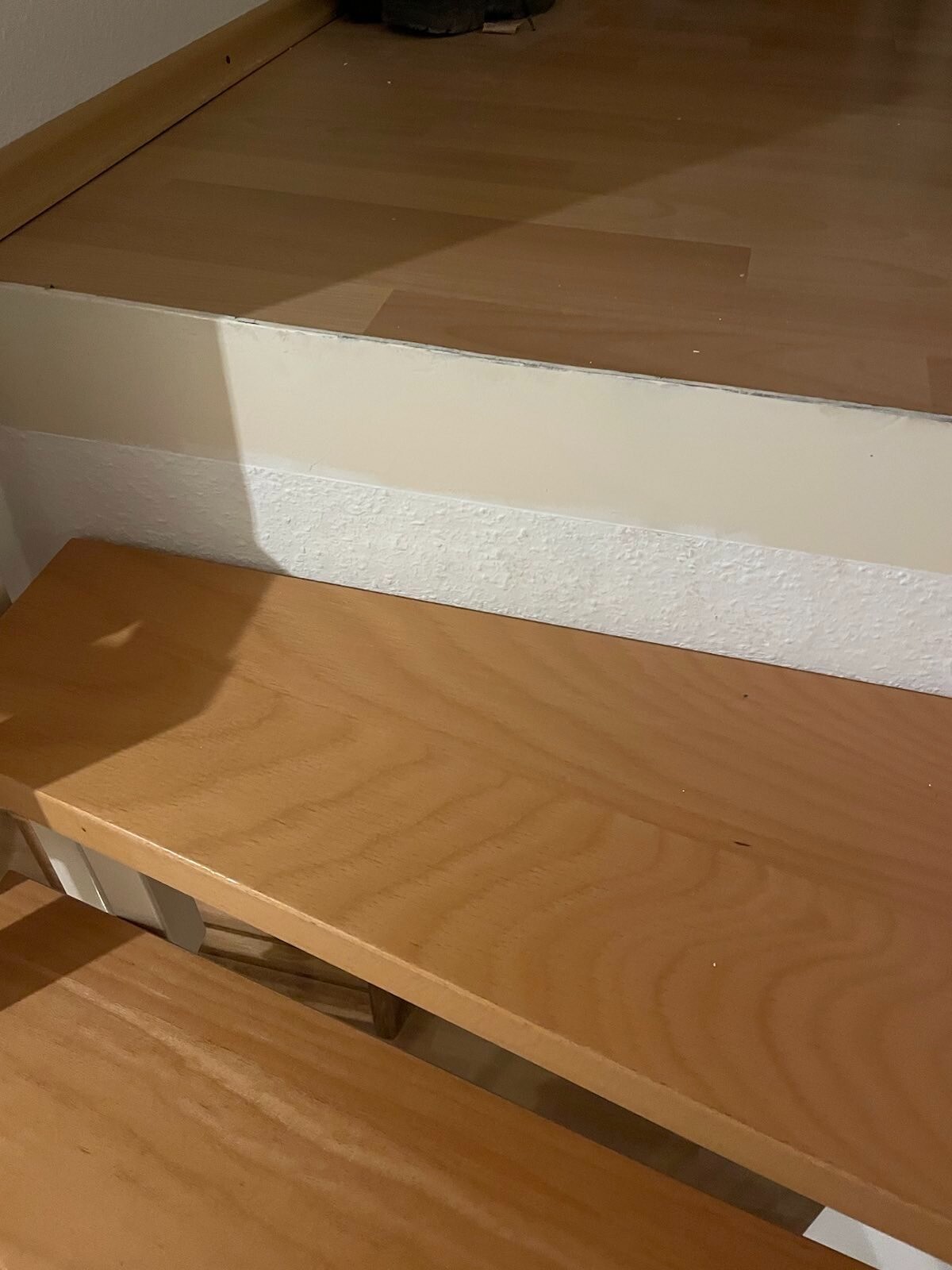 Holztreppe im Innenbereich mit hellbraunen Stufen und weißer Wand