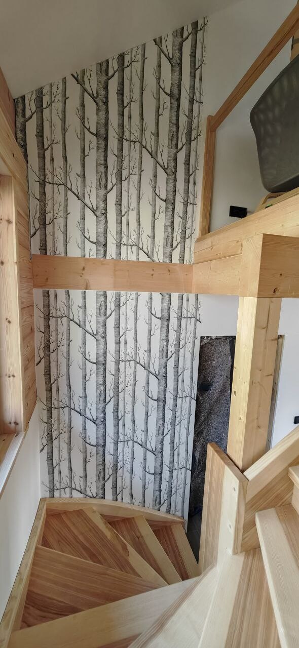 Helle Holztreppe im Innenraum vor einer Wand mit Birkenstamm-Tapete.