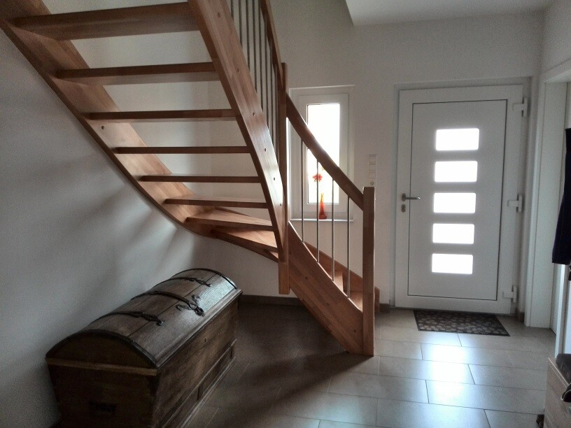 Eingangsbereich mit moderner Fronttür und sichtbarer Holztreppe