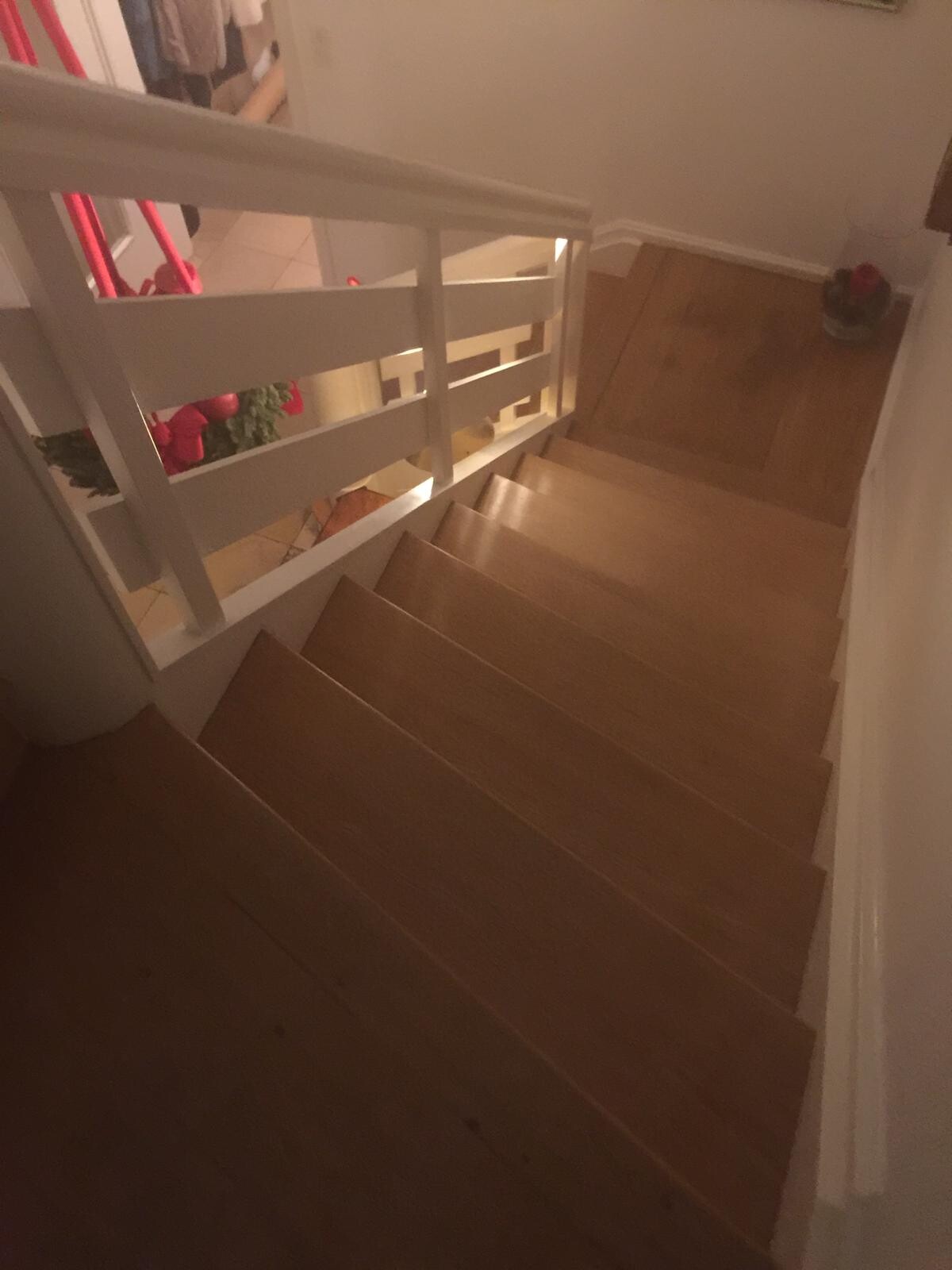 Holztreppe von oben mit weißem Geländer, Blick auf Flur unten.