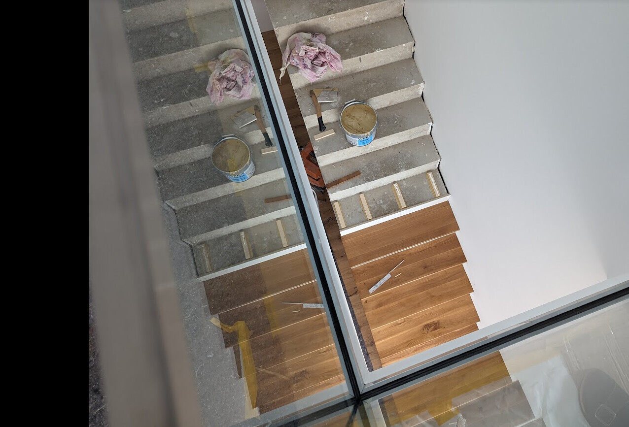 Treppe auf einer Baustelle mit Farbdosen, Pinsel, Lappen und Holzverkleidung.