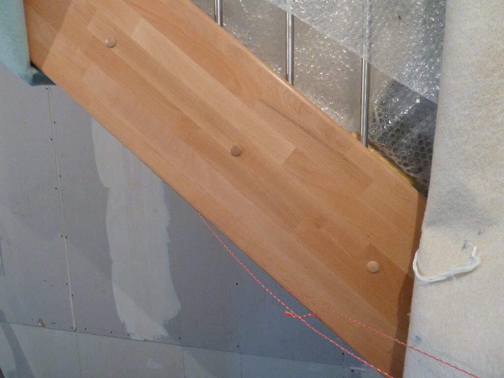 Unfertige Innenrenovierung mit Holztreppe, Trockenbauwänden und Dämmung sichtbar