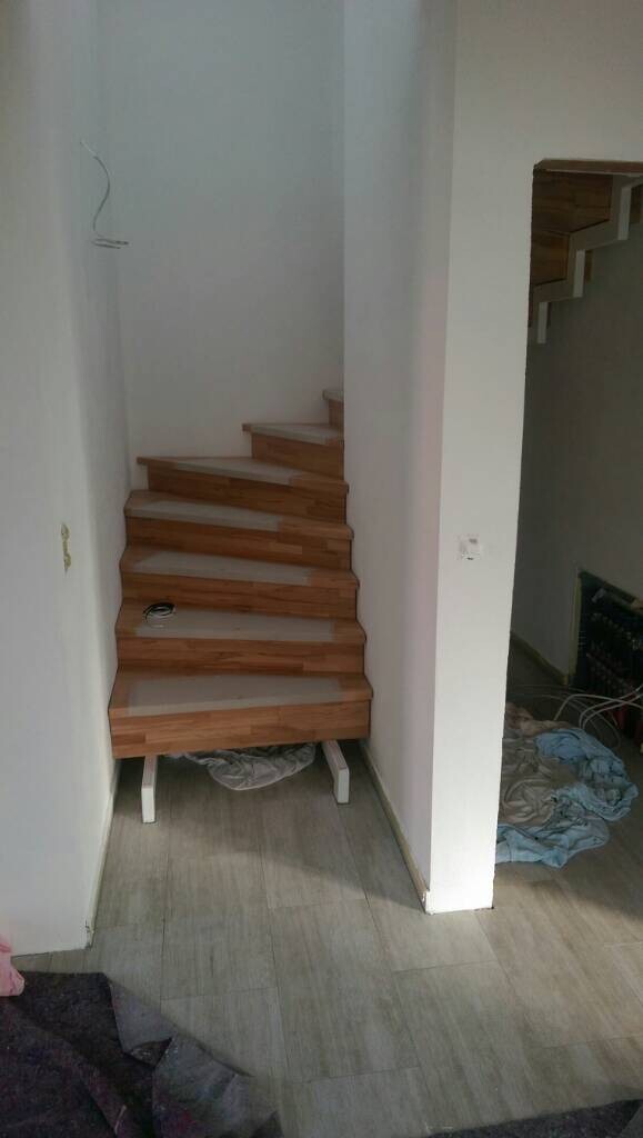 Holztreppe im Innenraum, Bauzustand, weiße Wände, Kleidung auf dem Boden.