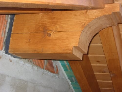 Detail eines Holzbauteils im Innenbereich mit gebogener Holzverkleidung an einer Treppe.