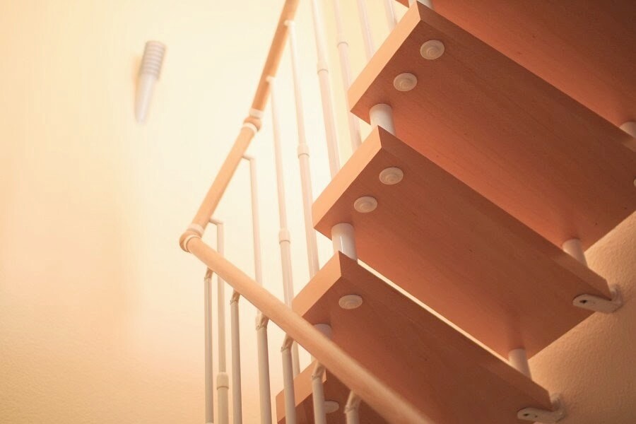Moderne Holztreppe mit weißen Geländern, warme Beleuchtung an der Wand.