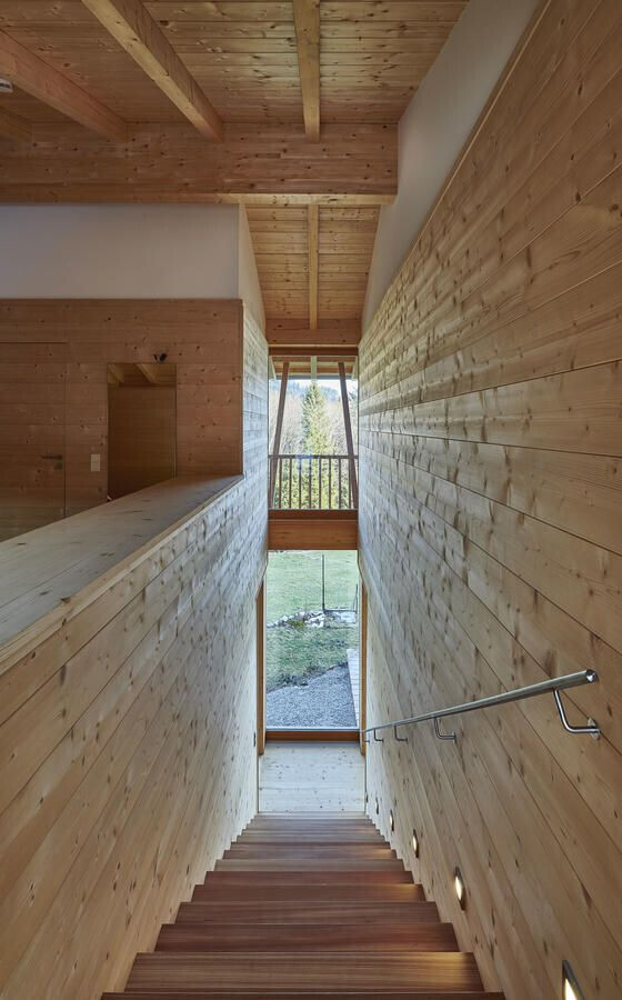 Holztreppe in einem Holzzimmer, seitliche Holzwände, Blick auf Glas-Tür zum Garten unten.