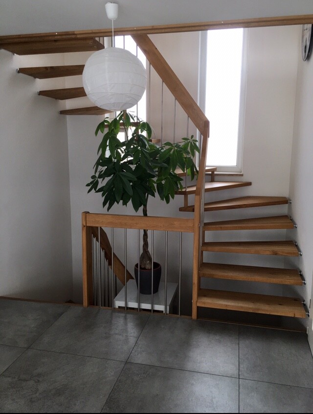 Offene Holztreppe mit großer Zimmerpflanze und weißer Papier-Laterne im Innenraum