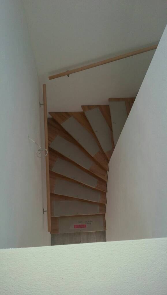 Schmale Holztreppe im Innenraum mit spiralförmigen Stufen und Geländer