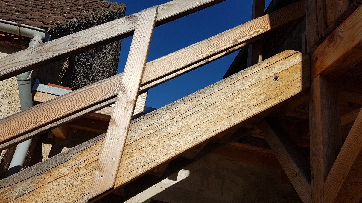 Holztreppe im Rohbau unter Bauarbeiten aus Balken, blauer Himmel sichtbar