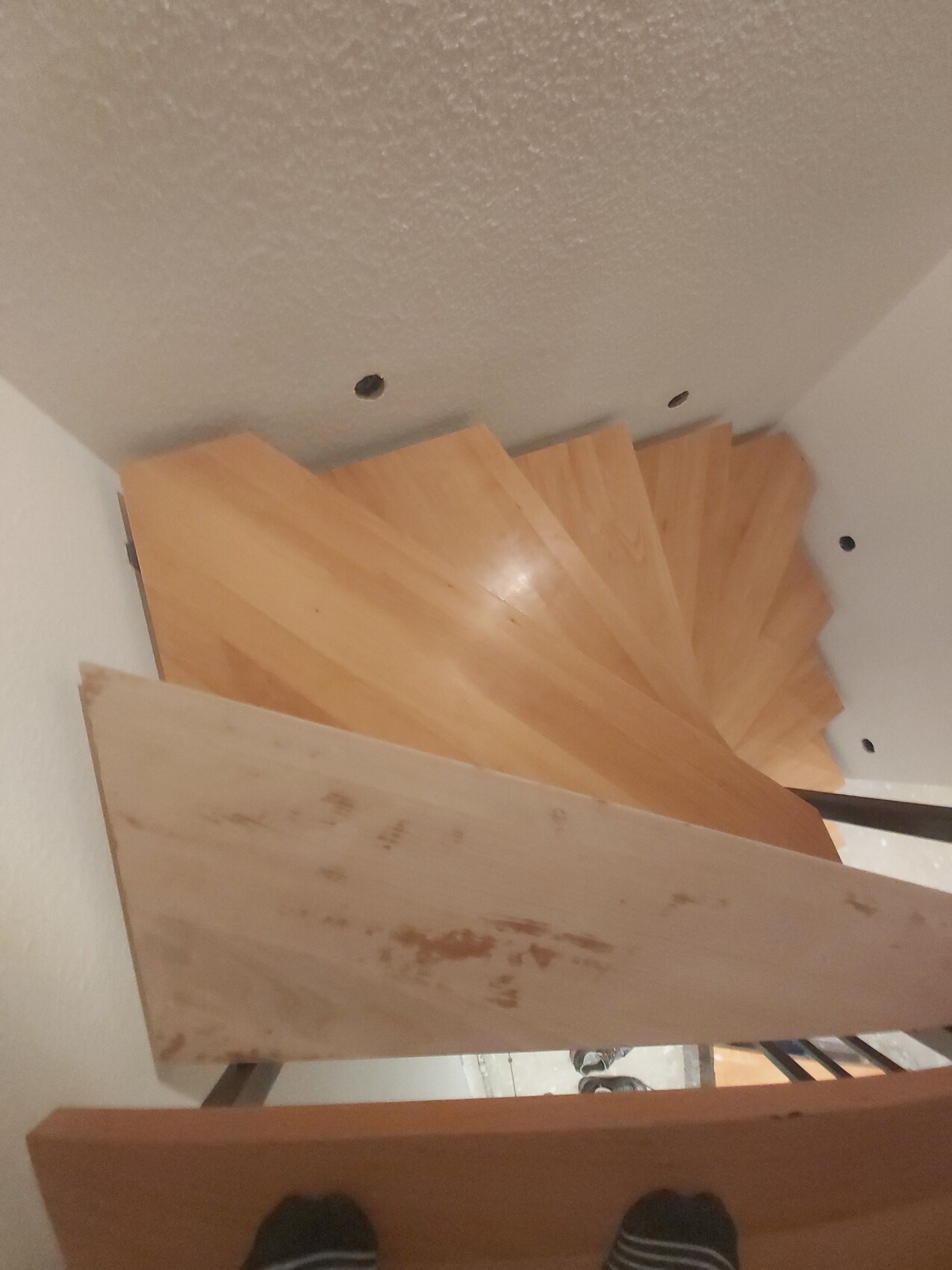 Spiralförmige Holztreppe im Innenraum, helle Holzstufen, Blick von oben auf Stufen