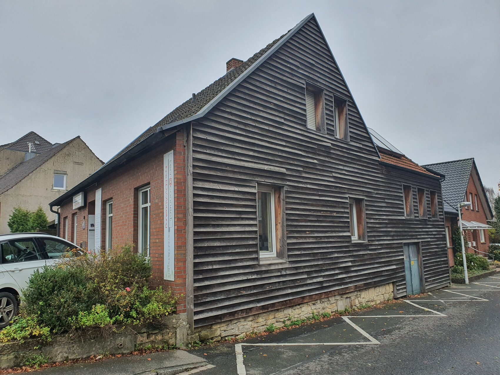 Außenansicht eines Gebäudes mit dunkler Holzverkleidung und Fenstern